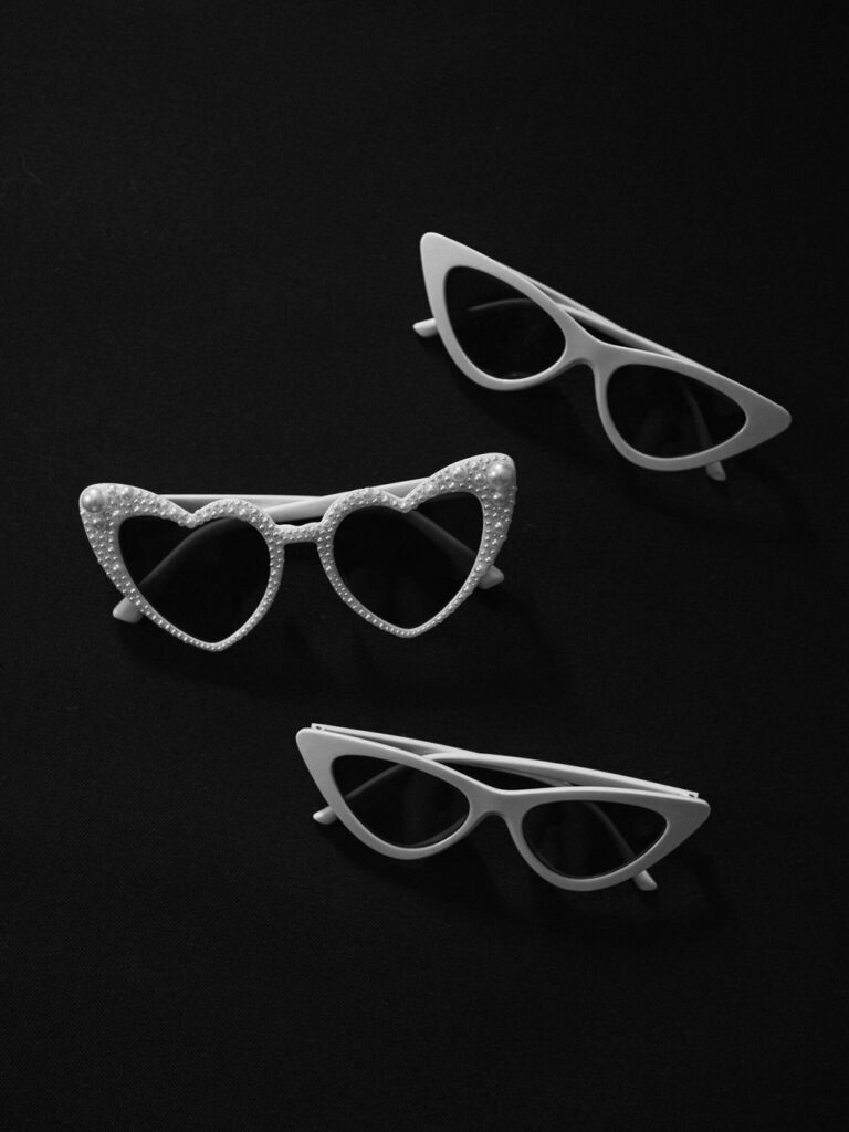 Three pairs of stylish sunglasses are displayed against a black background, including heart-shaped and cat-eye designs.