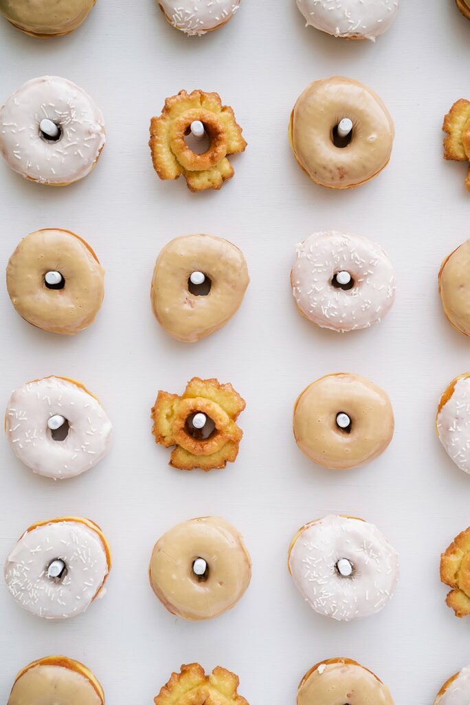 Assorted donuts with various icings and toppings arranged in a grid pattern on a white background.