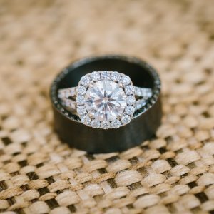Diamond ring with a halo of smaller diamonds inside a black ring, placed on a woven surface.