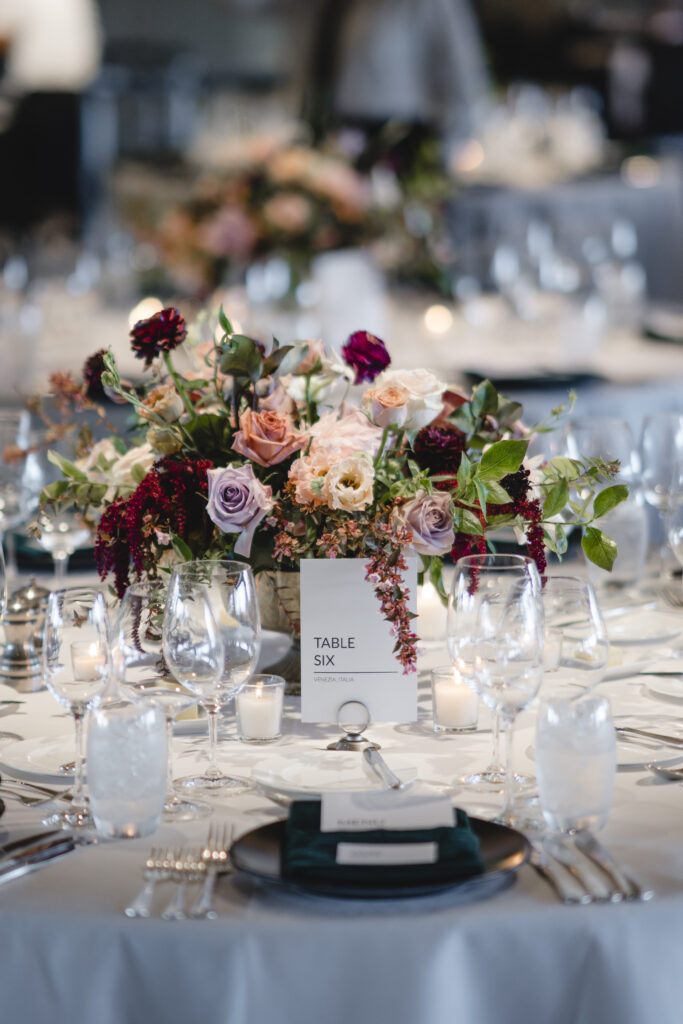 Elegant table setting with floral centerpiece, labeled "Table Six," surrounded by glassware, candles, and place settings.