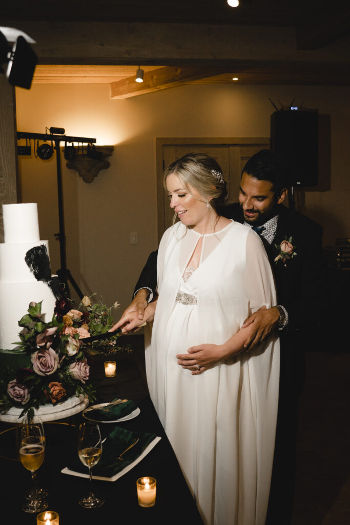 Bride and groom cutting a wedding cake together, surrounded by flowers and candles.