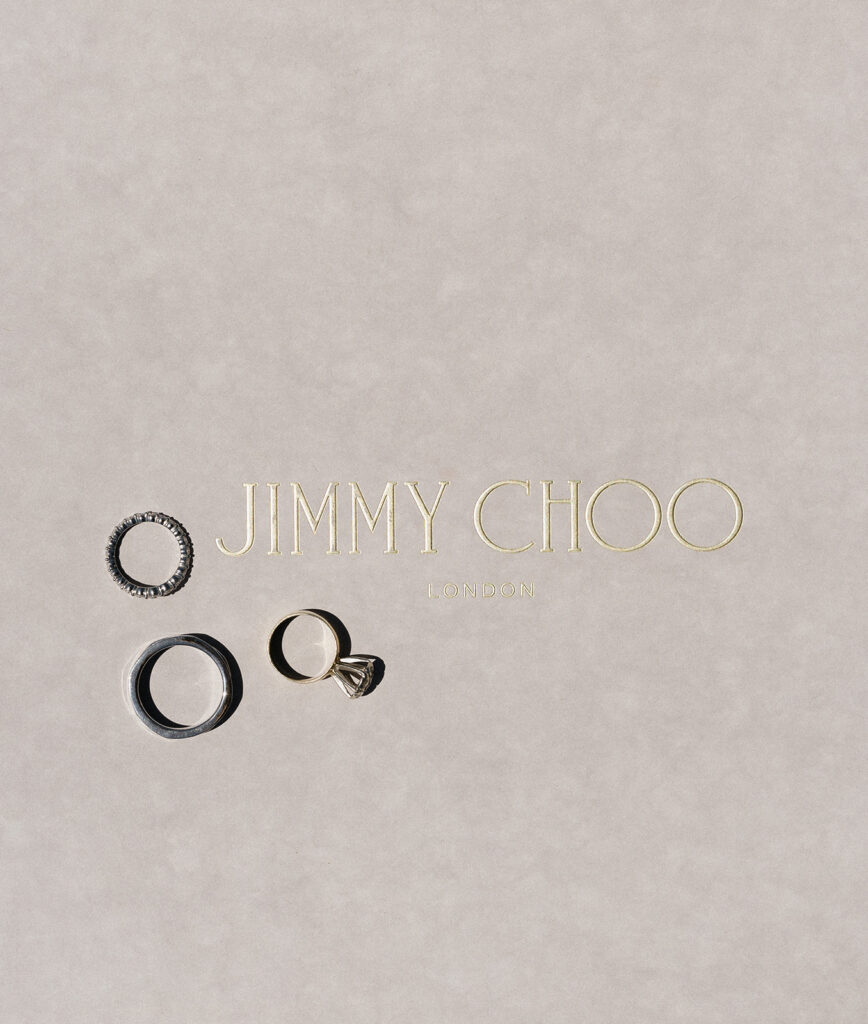 Three rings displayed on a surface with the text "Jimmy Choo London" in gold lettering.