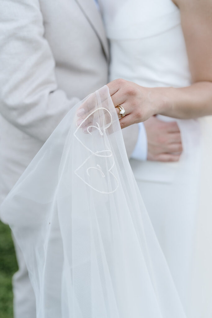A couple embraces with the bride holding a veil embroidered with two hearts.