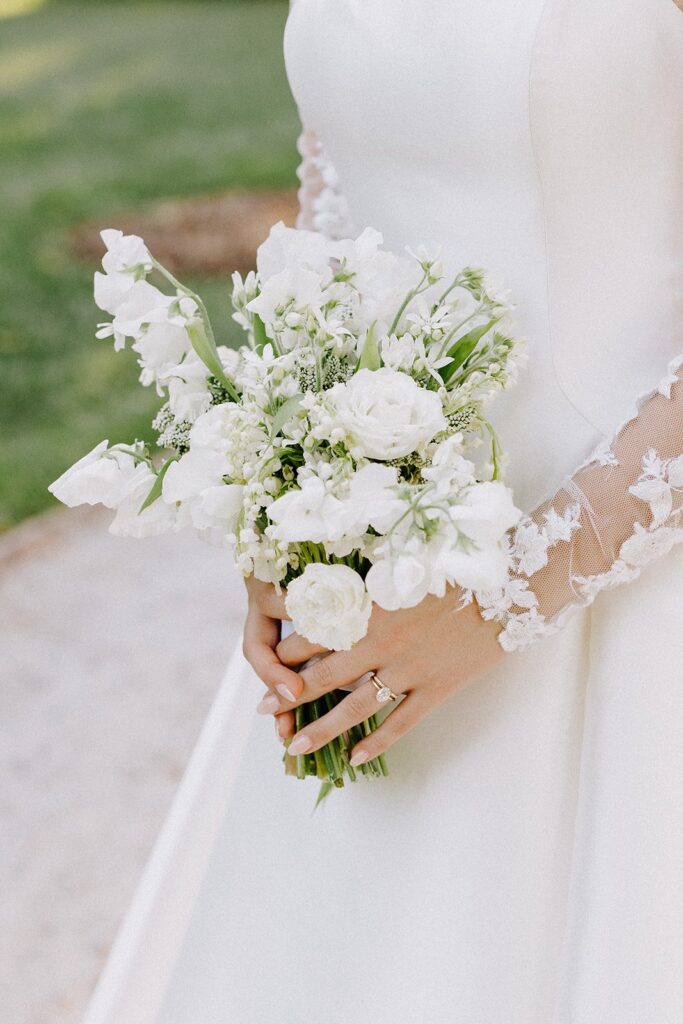 A bride in a white gown holds a bouquet of white flowers.