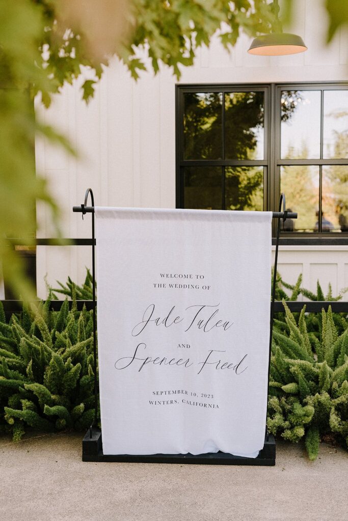 Wedding welcome sign for Jade Tulea and Spencer Freed on September 10, 2023, in Winters, California, displayed outdoors with greenery.