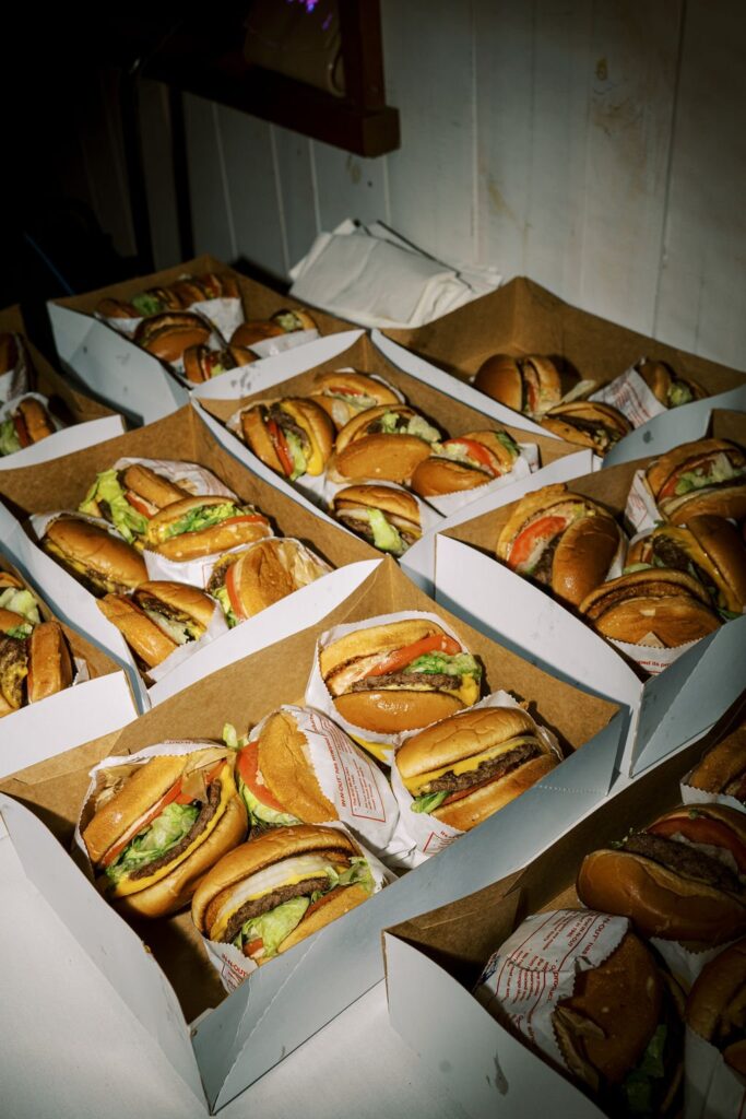Rows of boxed burgers with lettuce, tomato, and beef patties.