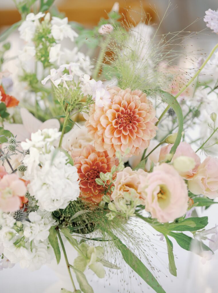 A bouquet featuring peach dahlias, white stock flowers, and green foliage.