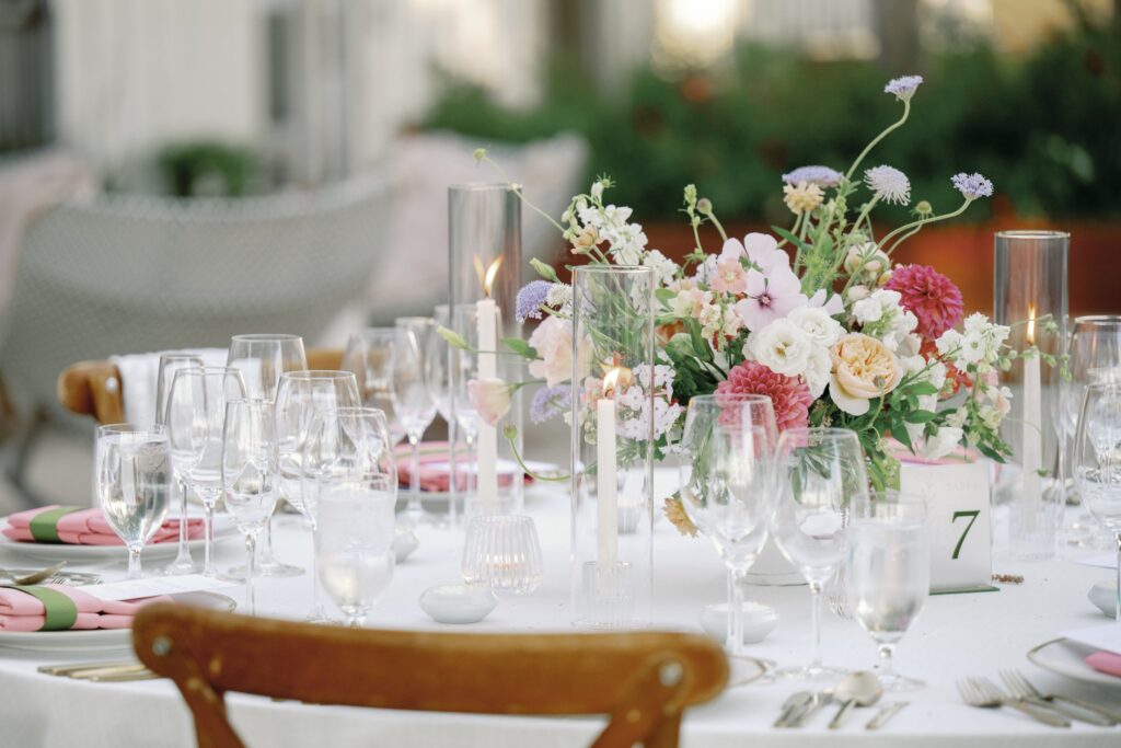 Elegant dining table setup with floral centerpiece, glassware, candles, and neatly arranged place settings.