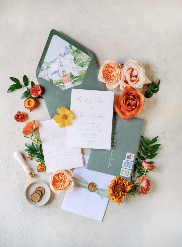 Wedding invitation suite with floral decorations, wax seals, and envelopes.