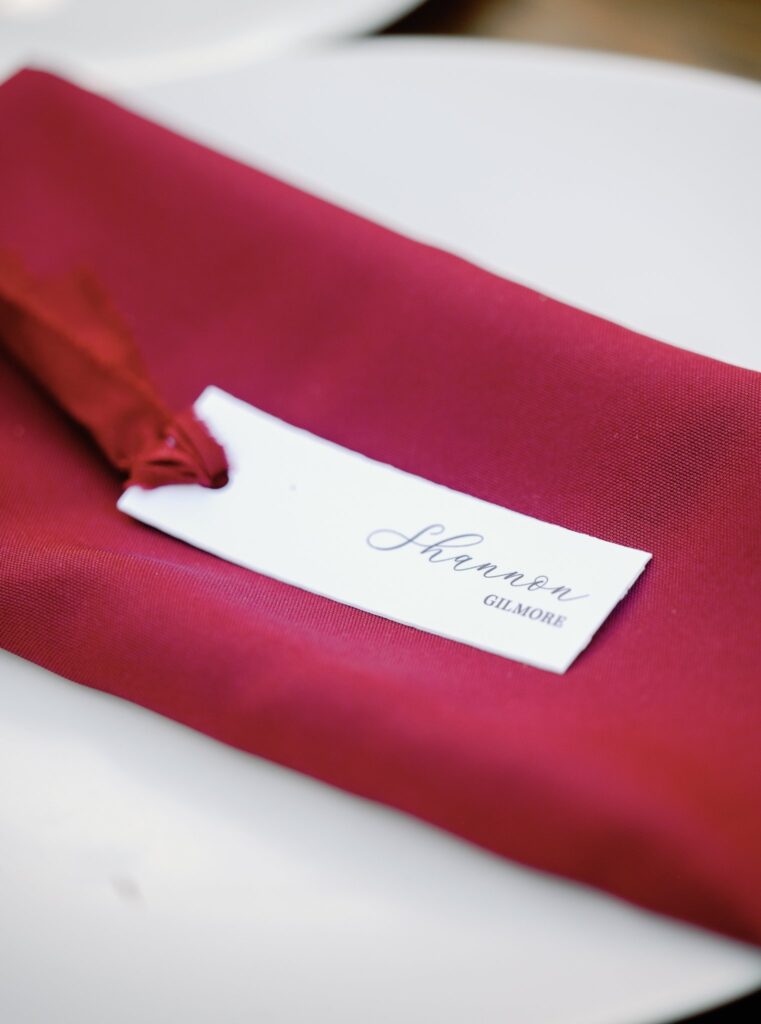 A red napkin with a place card reading "Shannon Gilmore" is set on a white plate.