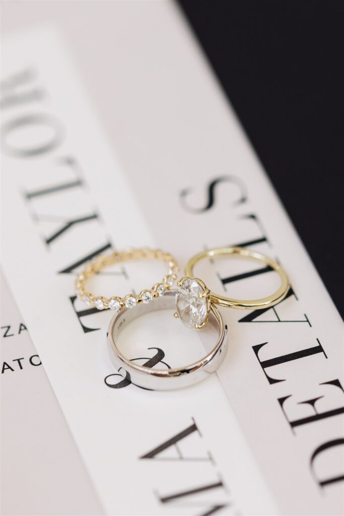 Three rings displayed on a book cover: a gold band with stones, a plain gold band, and a silver band with a large stone.