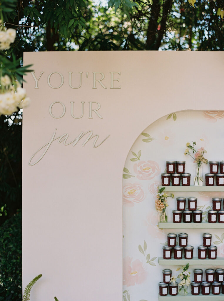 A display wall titled "You're Our Jam" holds shelves of small jam jars. The background features floral designs.