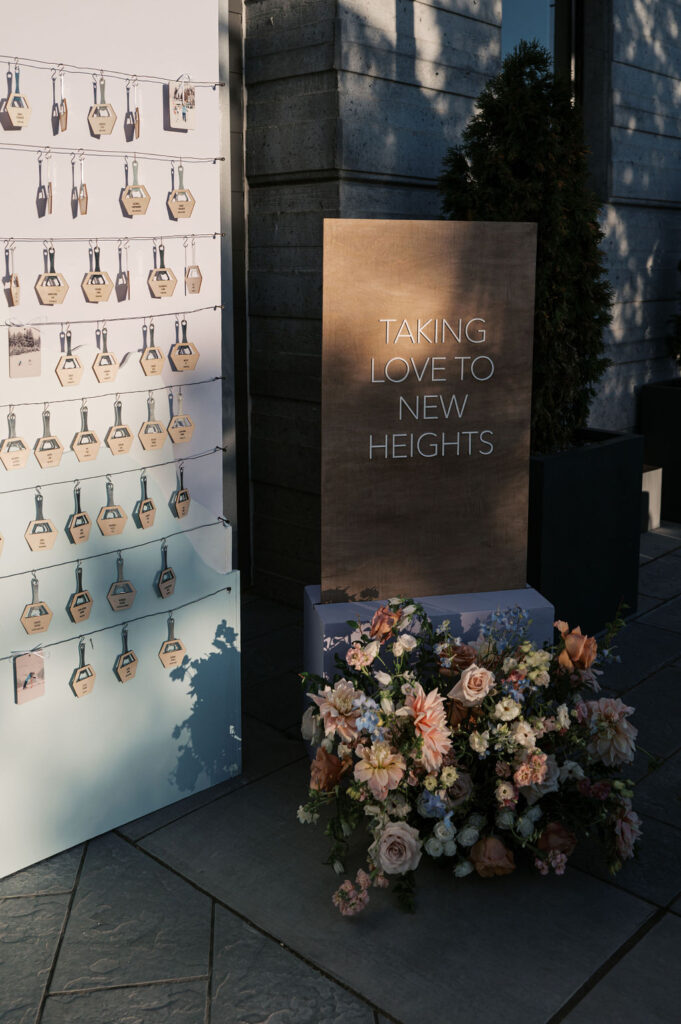 Display with seating tags and a sign that reads "Taking Love to New Heights," accompanied by a floral arrangement.