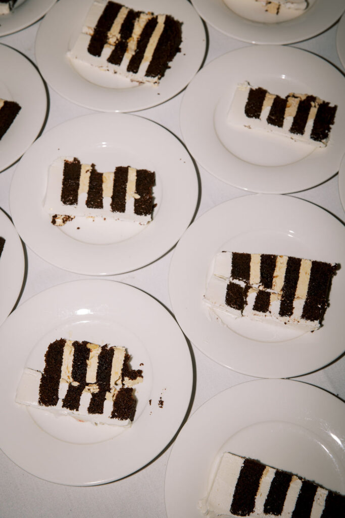 Slices of chocolate and vanilla layered cake served on white plates arranged on a table.