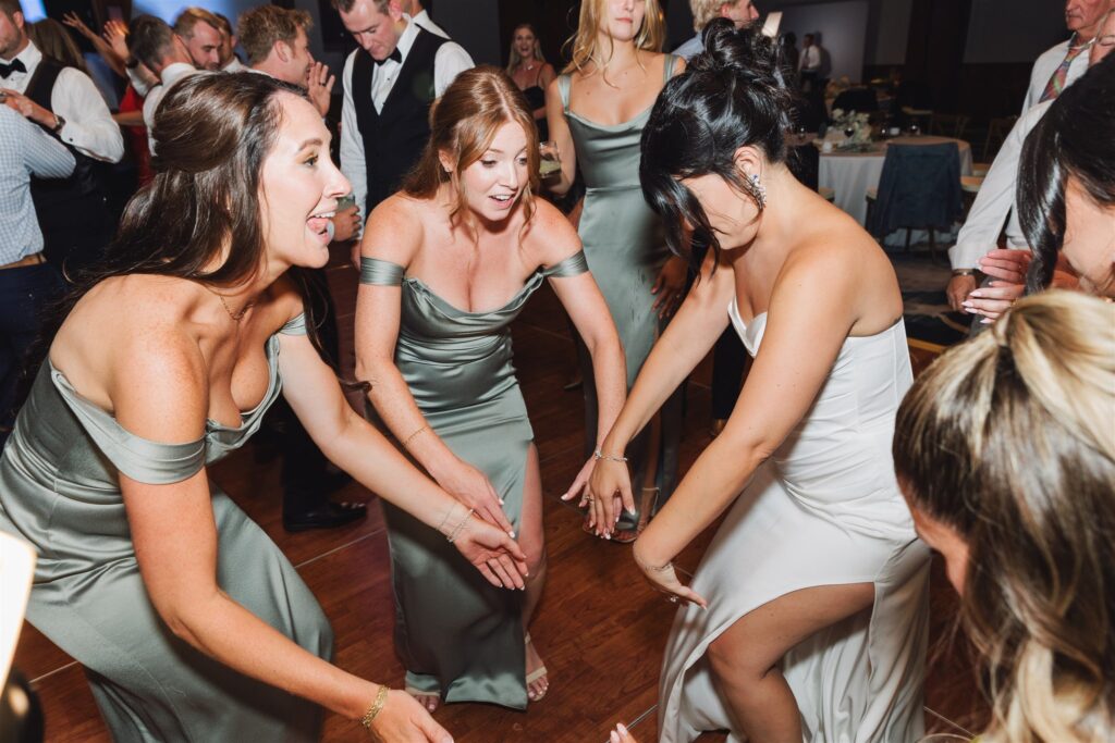 People in formal attire dancing energetically at an indoor event.