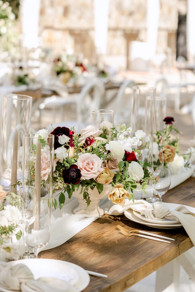 Elegant table setting with floral arrangements, tall candles, and neatly folded napkins on a wooden table.