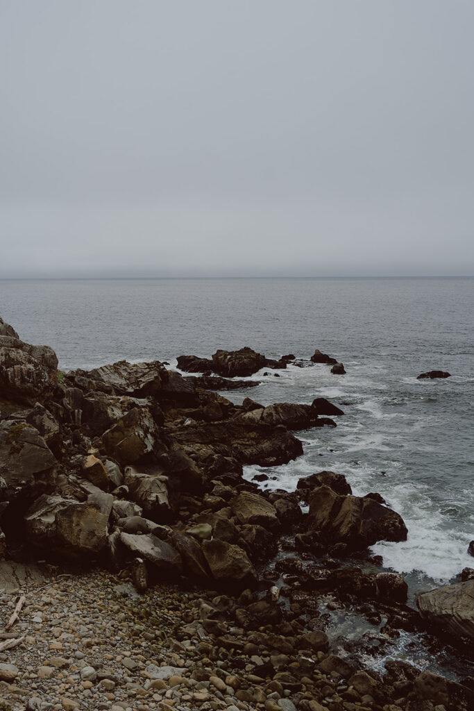 Rocky coastline under an overcast sky with waves gently crashing against the shore.