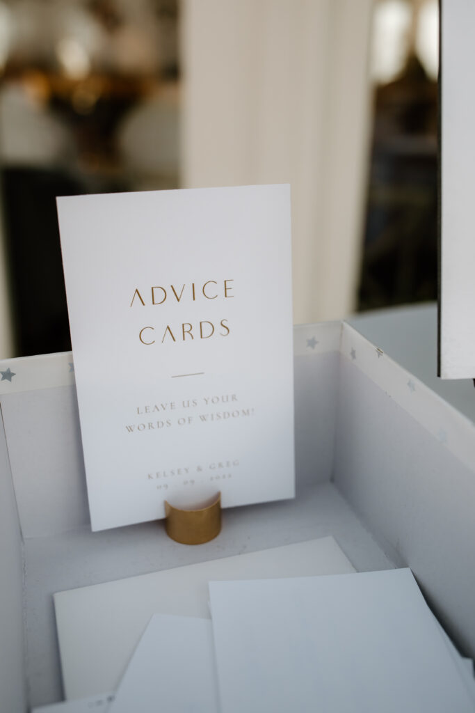 A small card titled "Advice Cards" prompts guests to leave words of wisdom. It stands upright in a holder on a table.