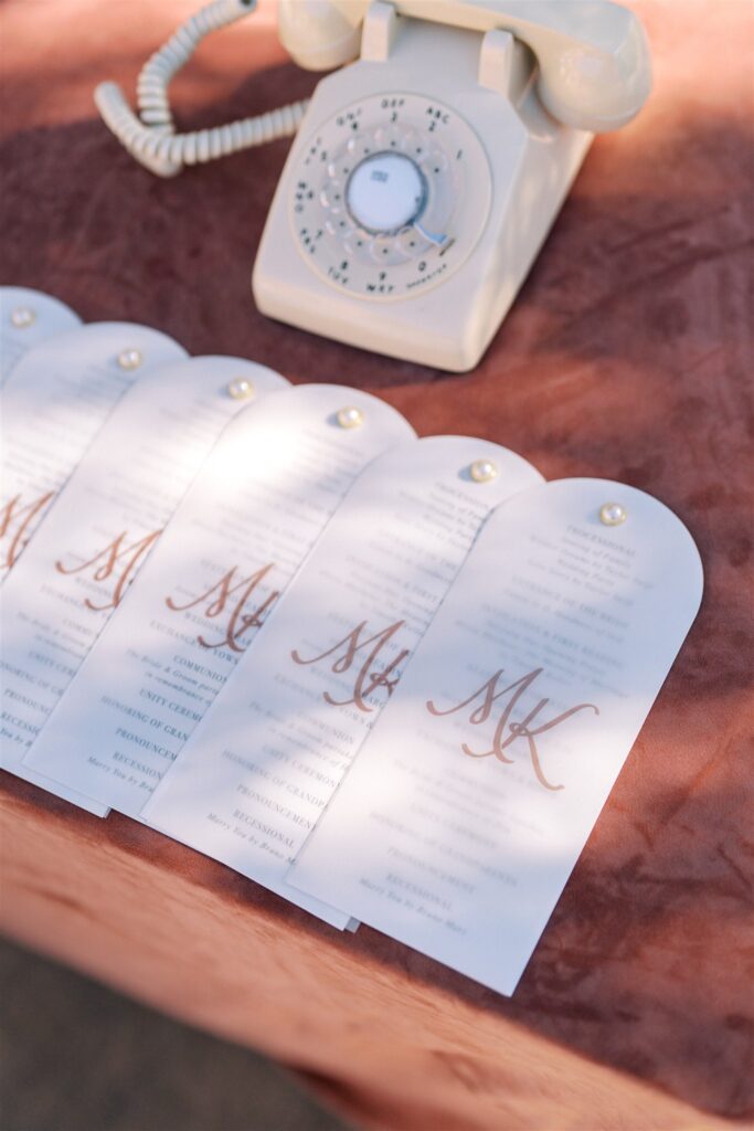 Vintage rotary phone on a table with several customized translucent bookmarks featuring an "MK" monogram.