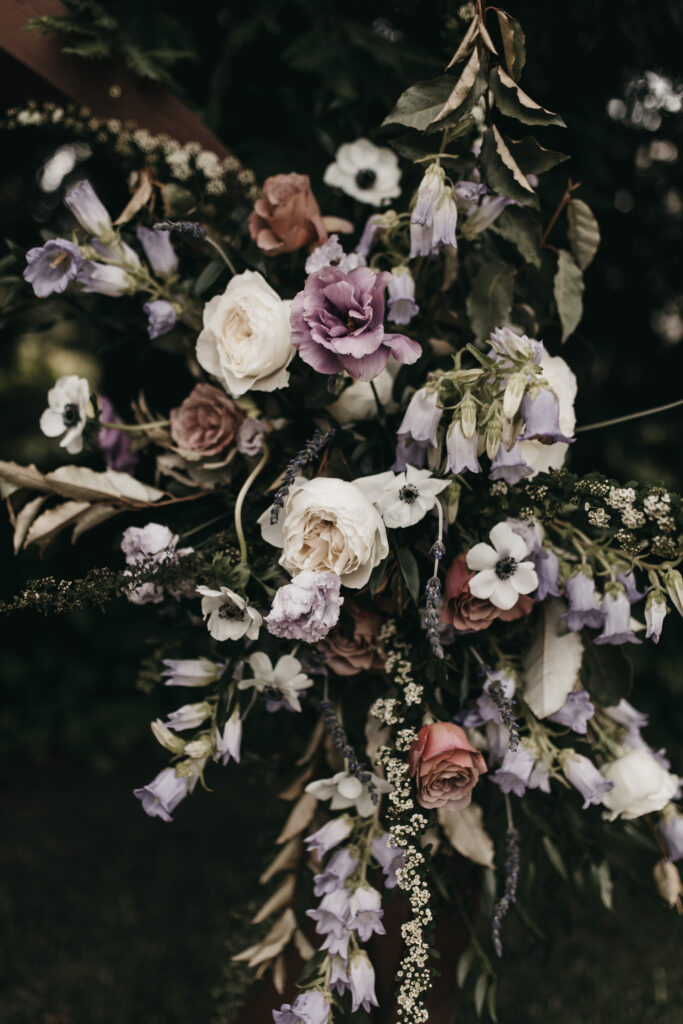 A bouquet featuring white, purple, and pink flowers with lush green foliage in the background.