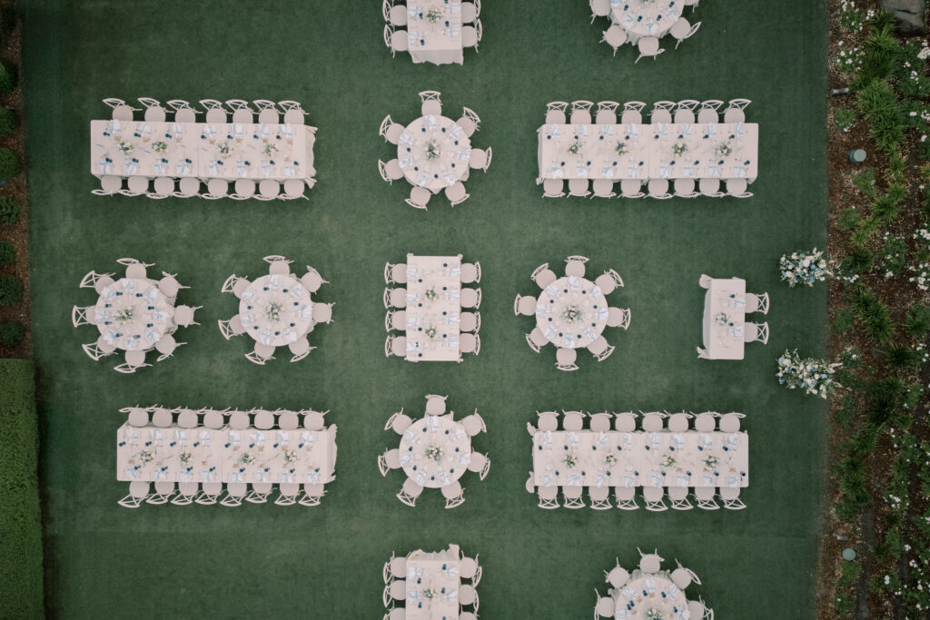Aerial view of a Solage Calistoga wedding setup with rectangular and round tables arranged on grass, each table set with chairs, plates, and glassware.