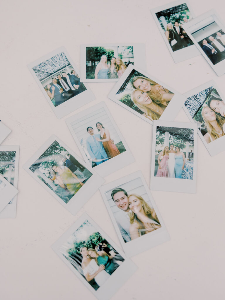 Scattered instant photos on a white surface, showing groups of people posing and smiling outdoors at a Solage Calistoga wedding.